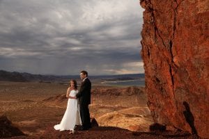 A bride and groom posing in front of a rock formation.
