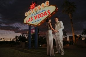 A bride and groom standing in front of the las vegas sign.