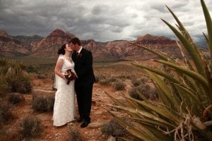 A bride and groom kissing in the desert.