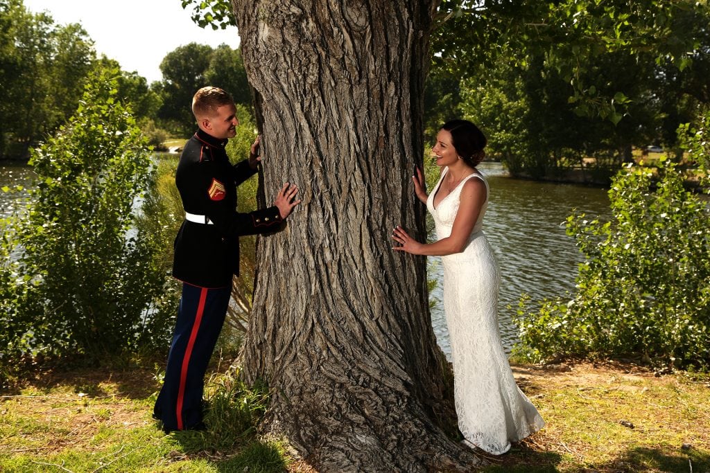 A bride and groom leaning against a tree.