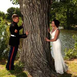 A bride and groom leaning against a tree.