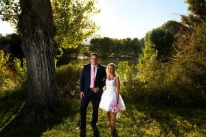 A bride and groom posing in front of a tree.