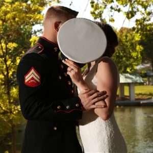 A bride and groom kissing in front of a pond.