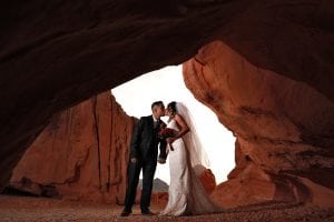 A bride and groom kissing in a cave.