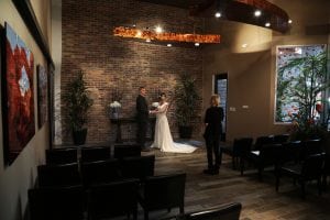 A bride and groom standing in front of a brick wall.