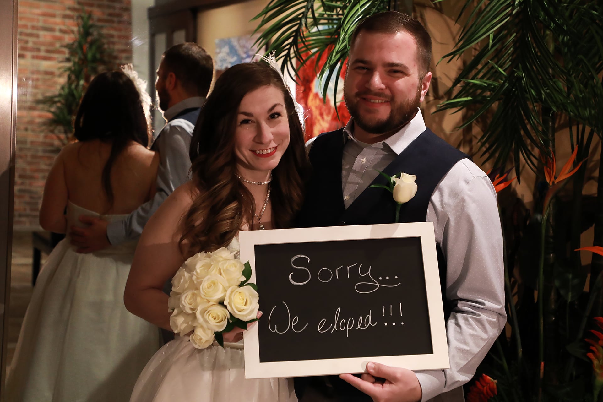 A bride and groom holding a sign.