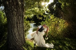 A bride and groom kissing in front of a tree.