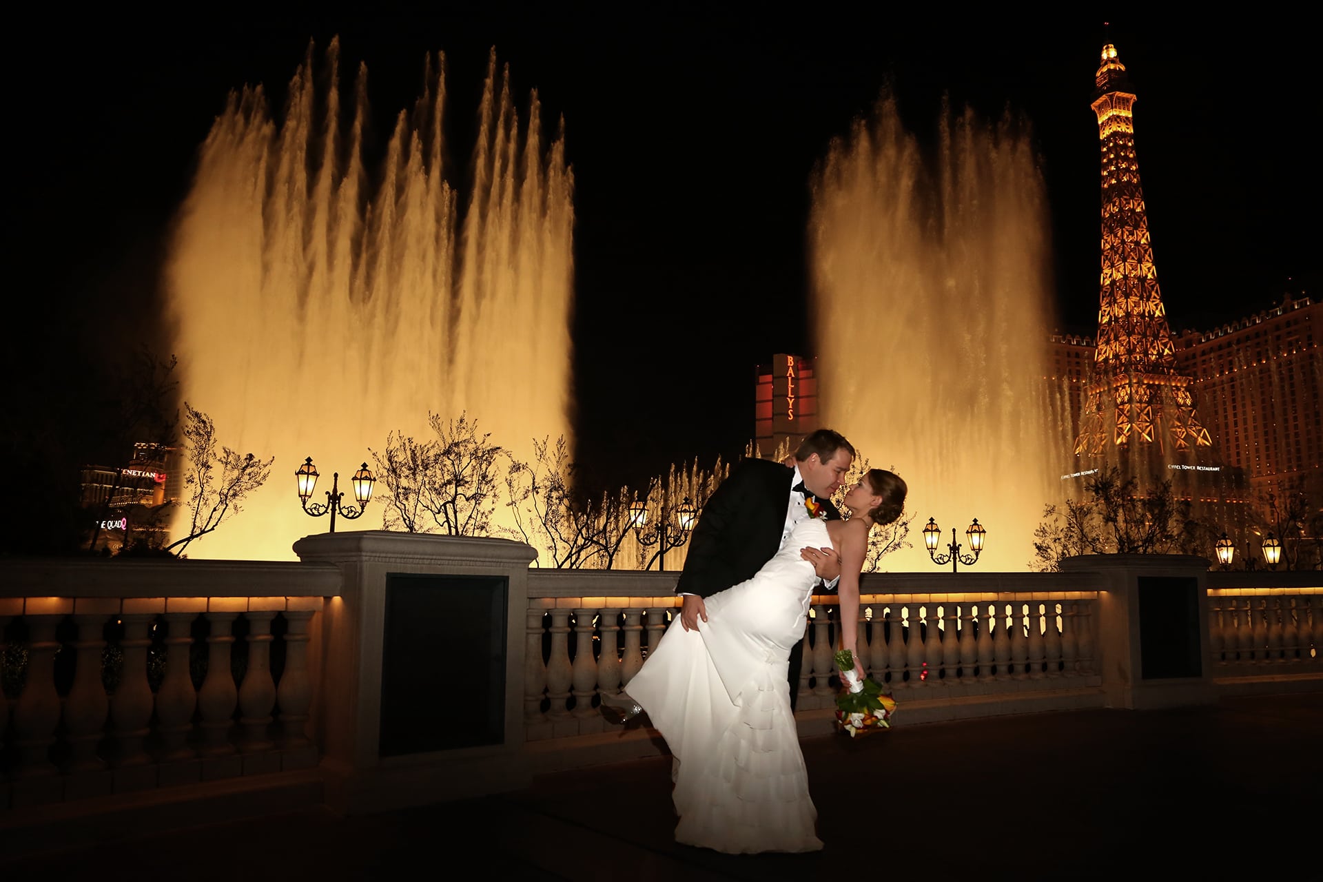 A bride and groom kissing in front of a fountain in las vegas.