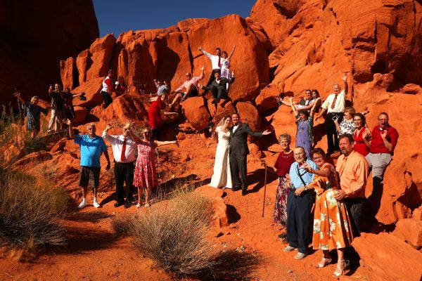 A group of people celebrating a wedding in front of a stunning red rock formation at Valley of Fire.