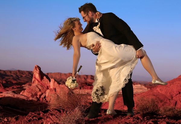 A bride and groom hugging in the desert.