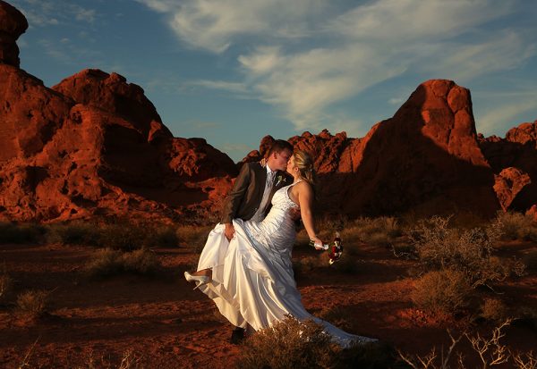 A bride and groom kissing in the desert.