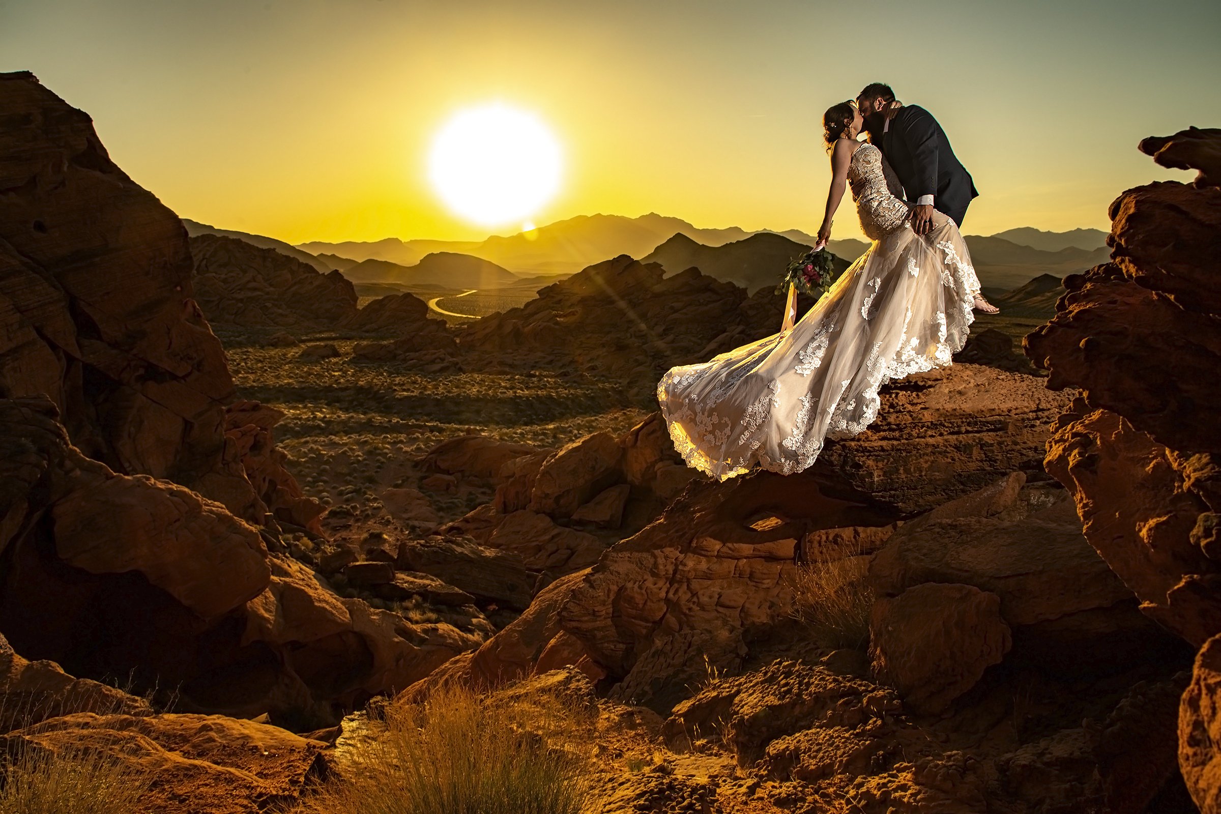 A couple passionately kisses during their scenic Las Vegas wedding at sunset in the desert.