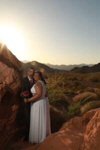 A bride and groom posing in front of a rock formation.
