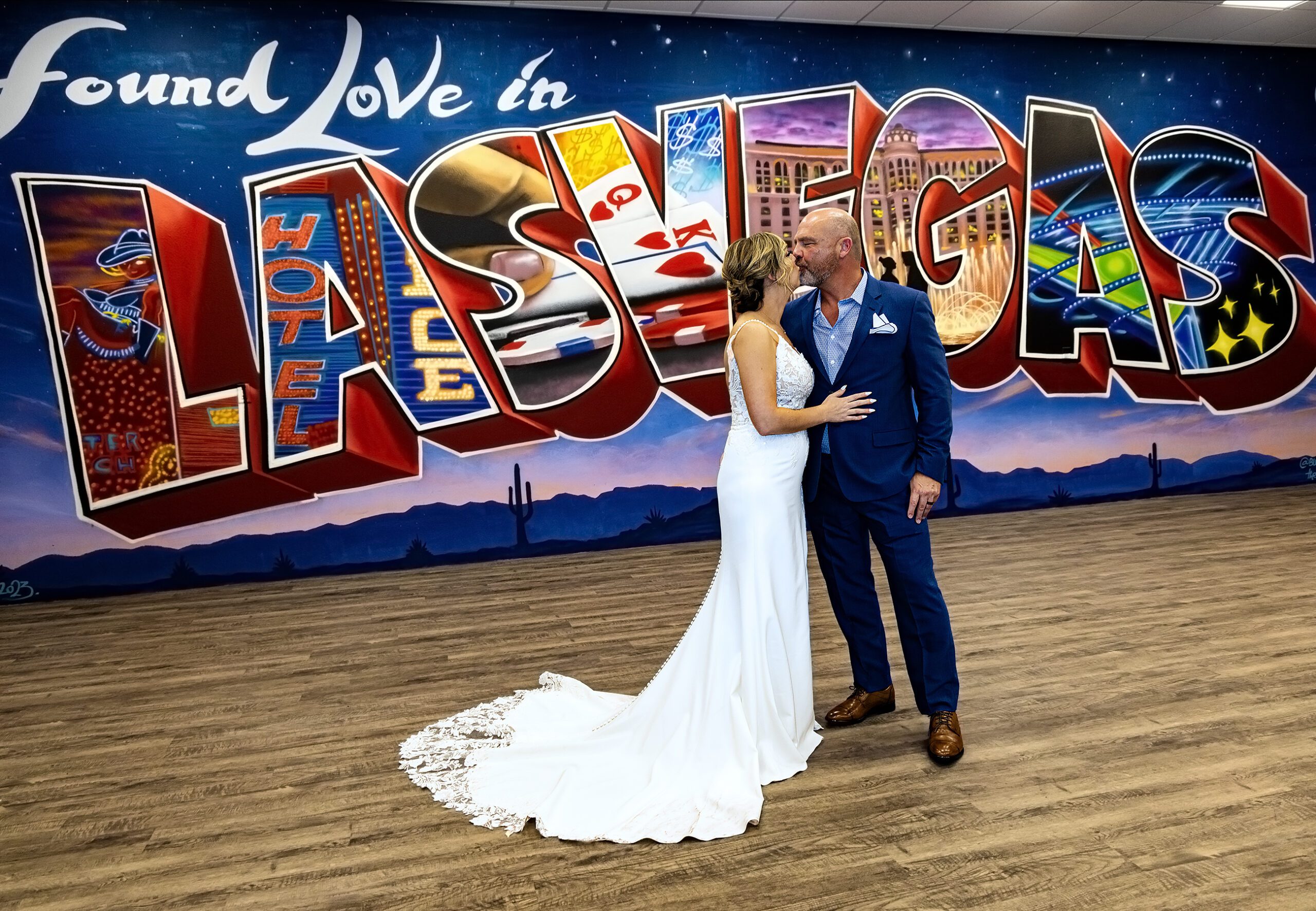 A bride and groom standing in front of a mural of las vegas.