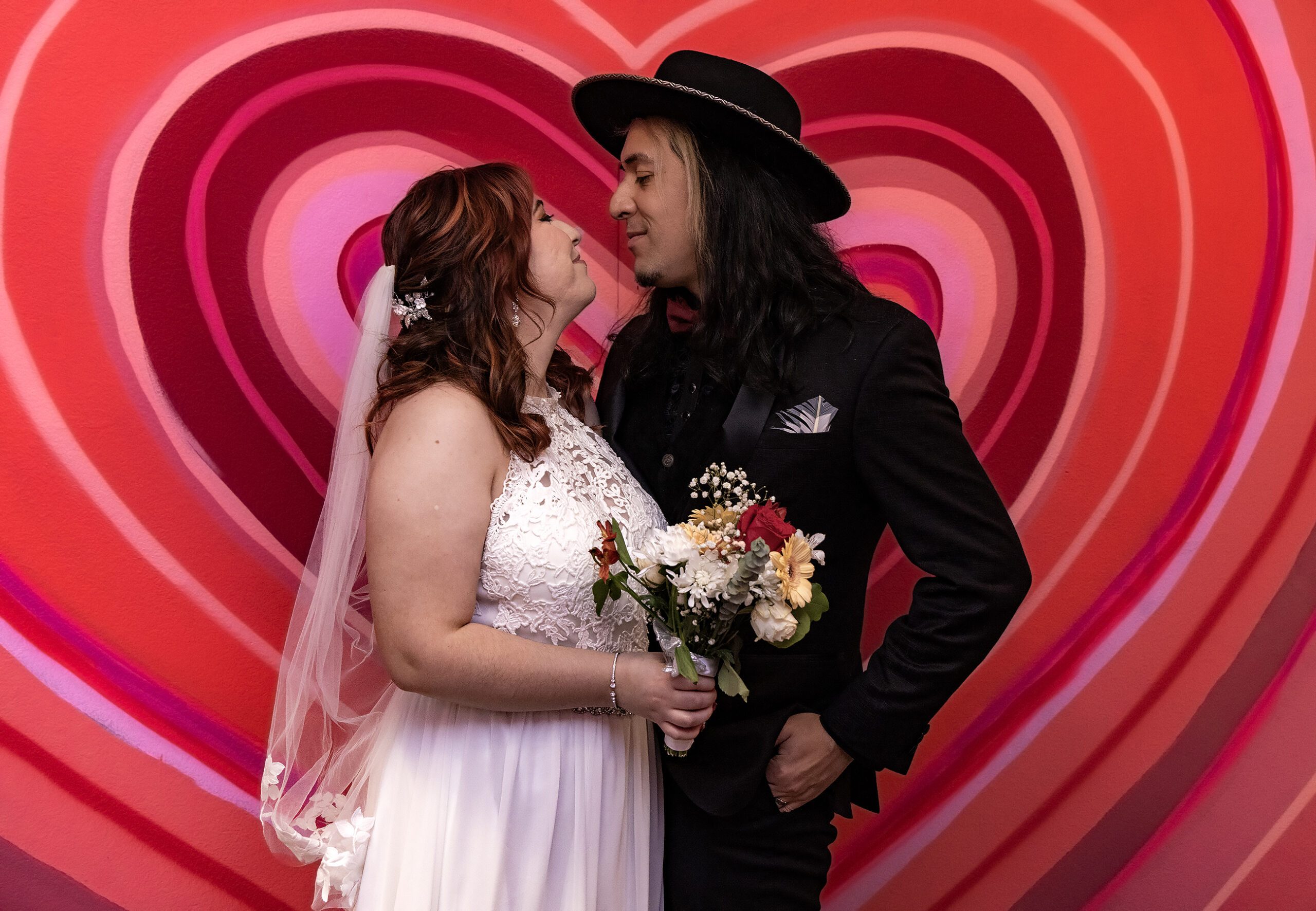 A bride and groom share an affectionate moment in front of a heart-patterned background at one of the wedding chapels in Las Vegas.
